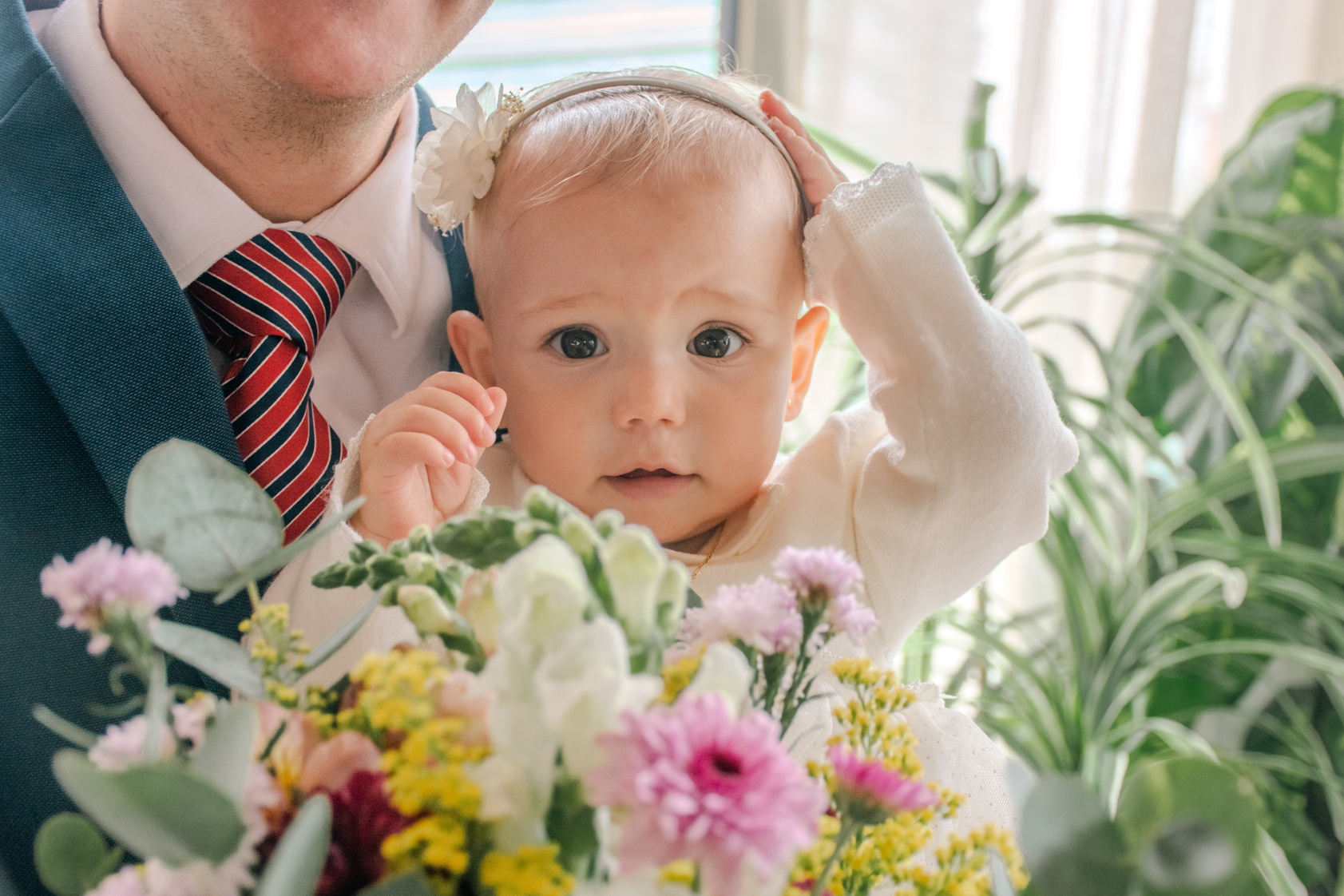 Bebé en su bautizo, junto a su familia y flores