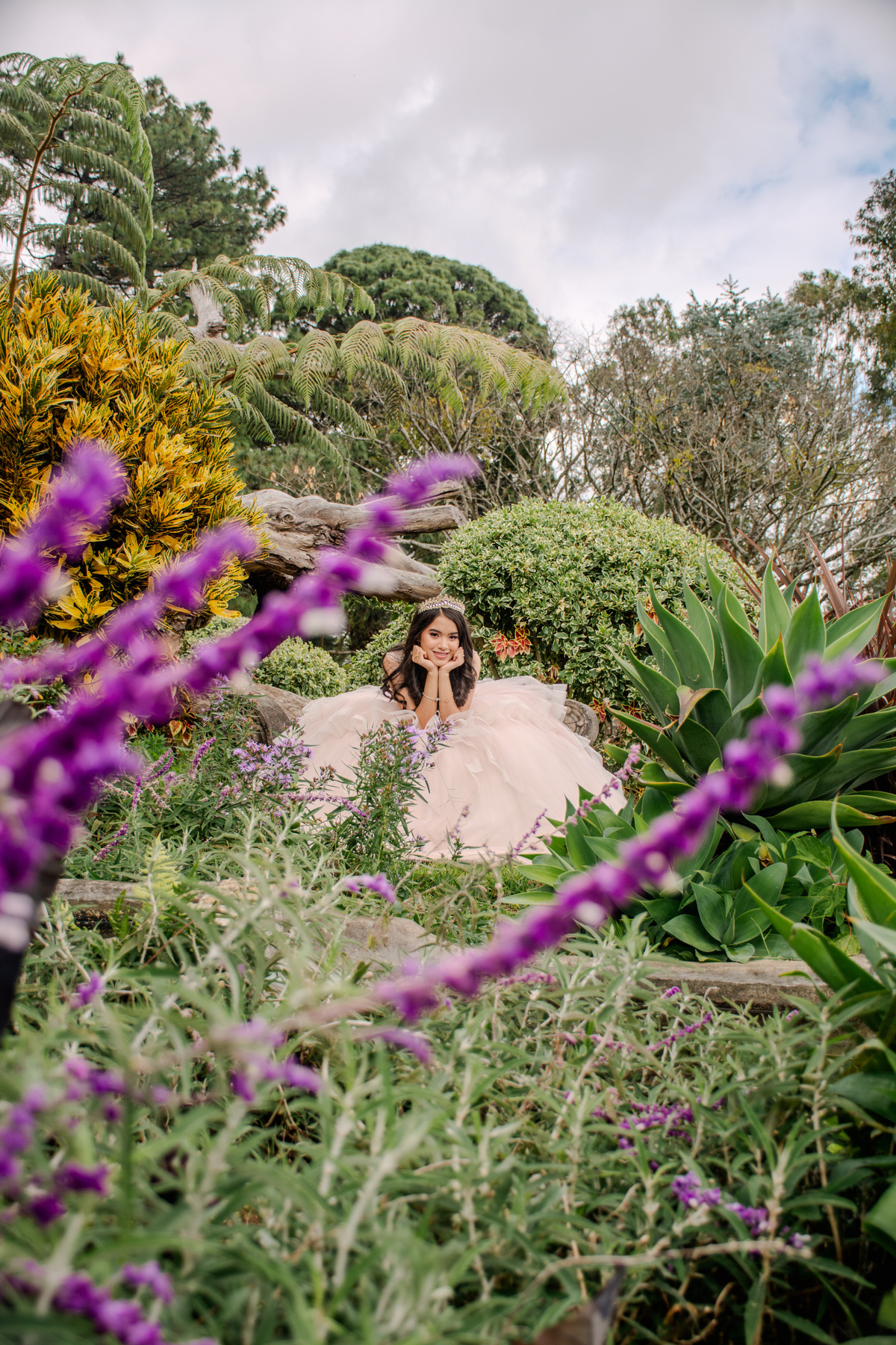 Quinceañera entre flores con un vestido rosa